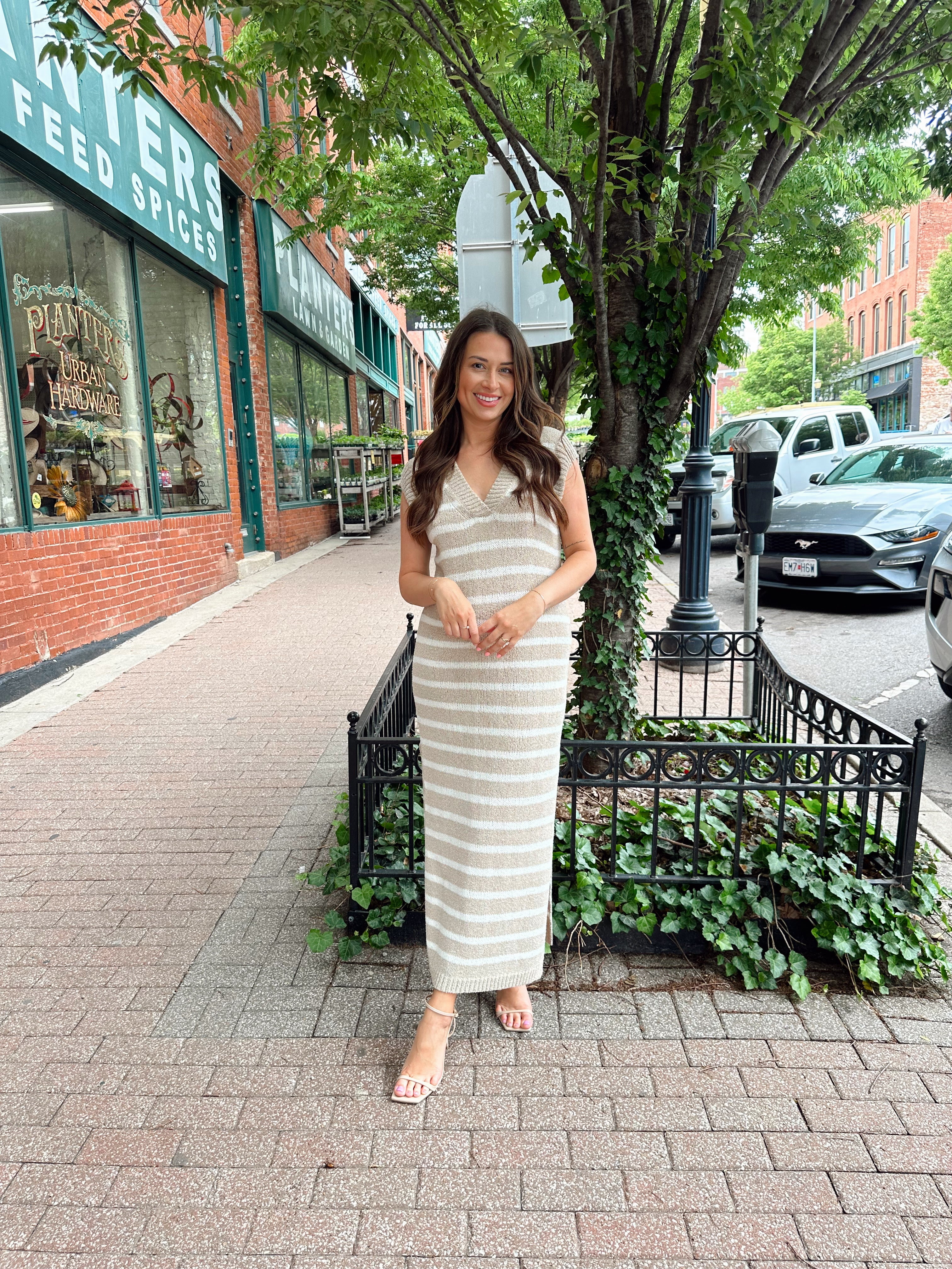 Woman wearing a beige and white striped knit midi dress with a V-neck and side slit