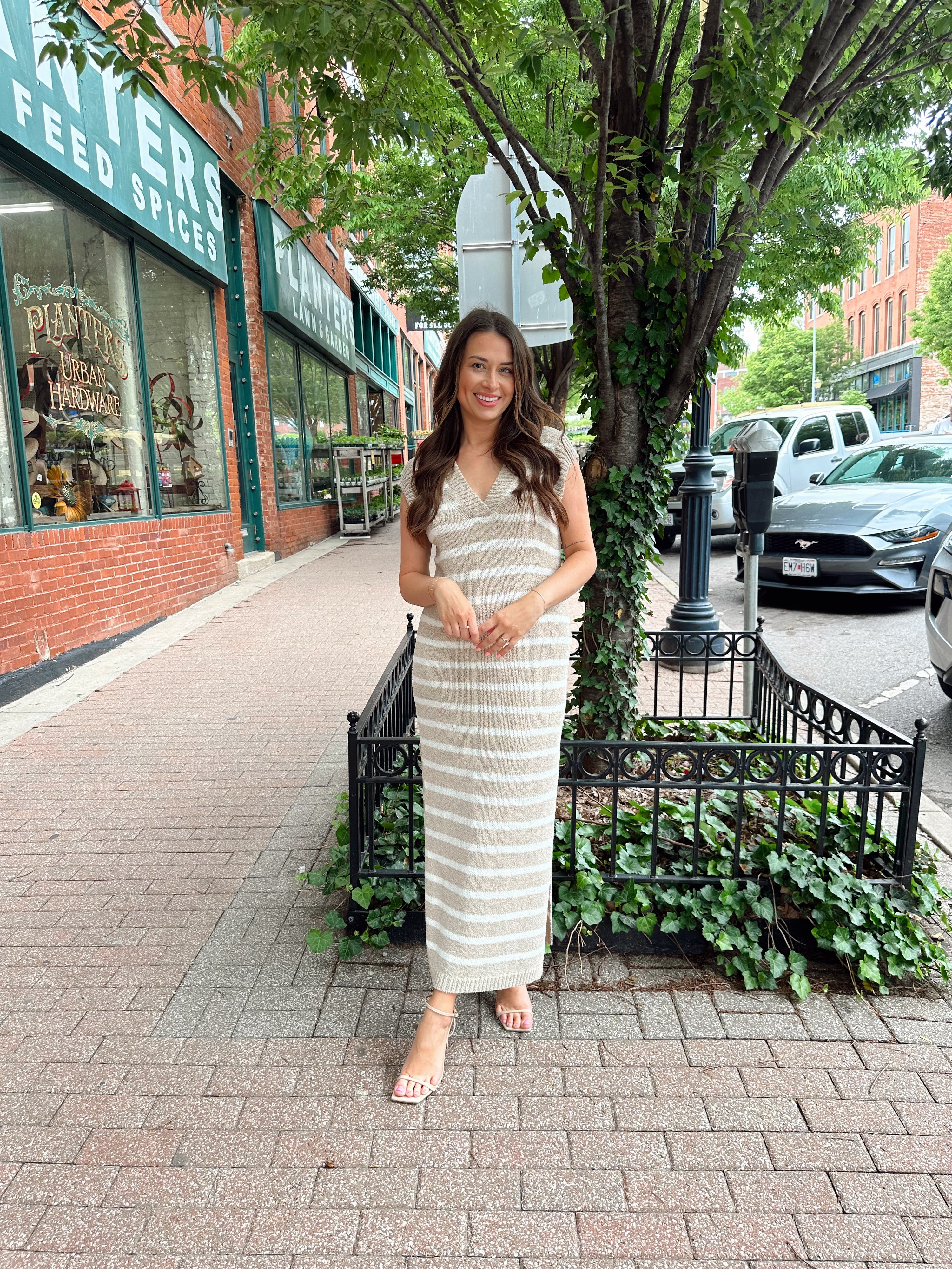 Woman wearing a beige and white striped knit midi dress with a V-neck and side slit