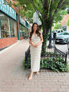 Woman wearing a beige and white striped knit midi dress with a V-neck and side slit