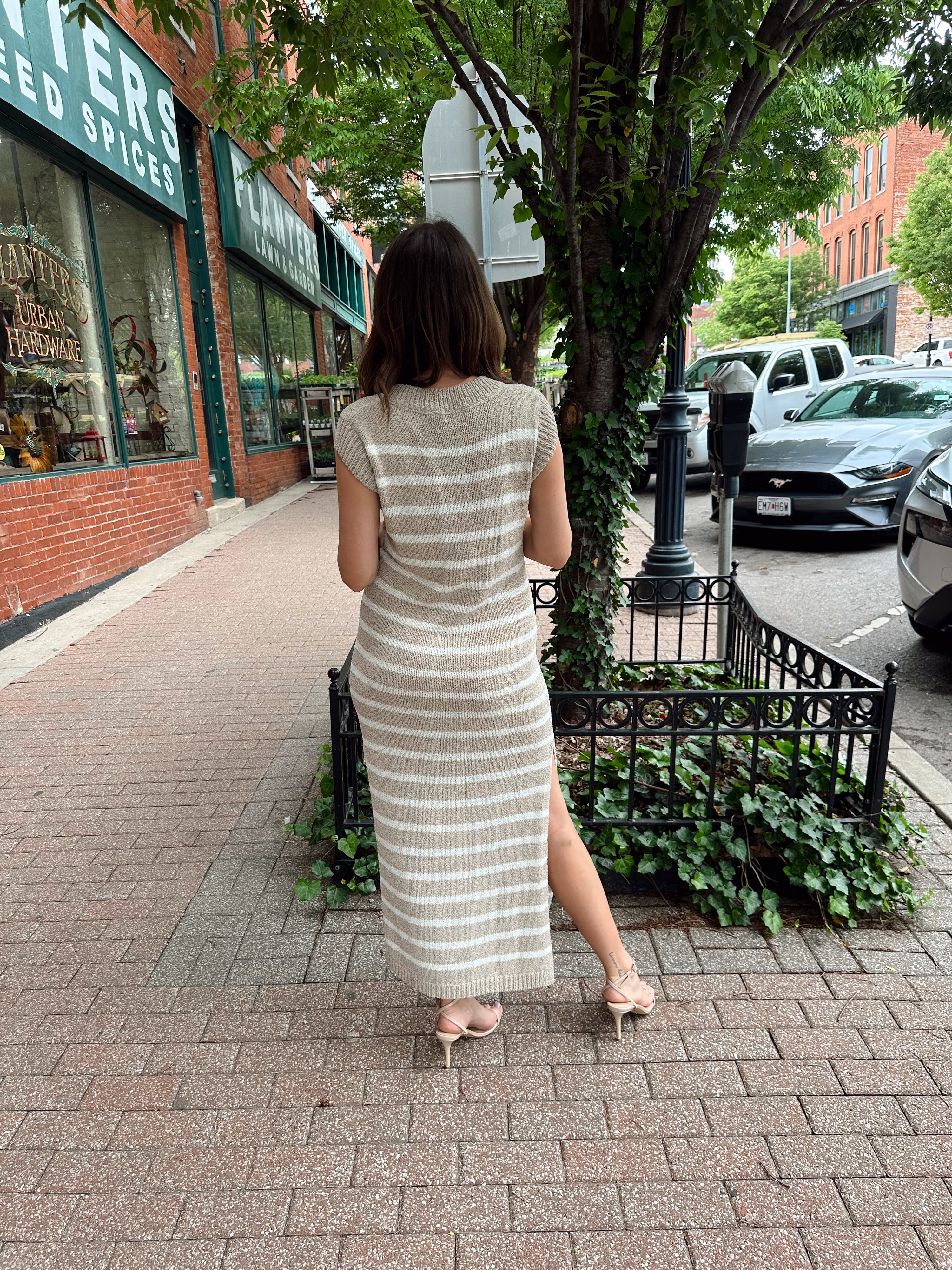 Woman wearing a beige and white striped knit midi dress with a V-neck and side slit