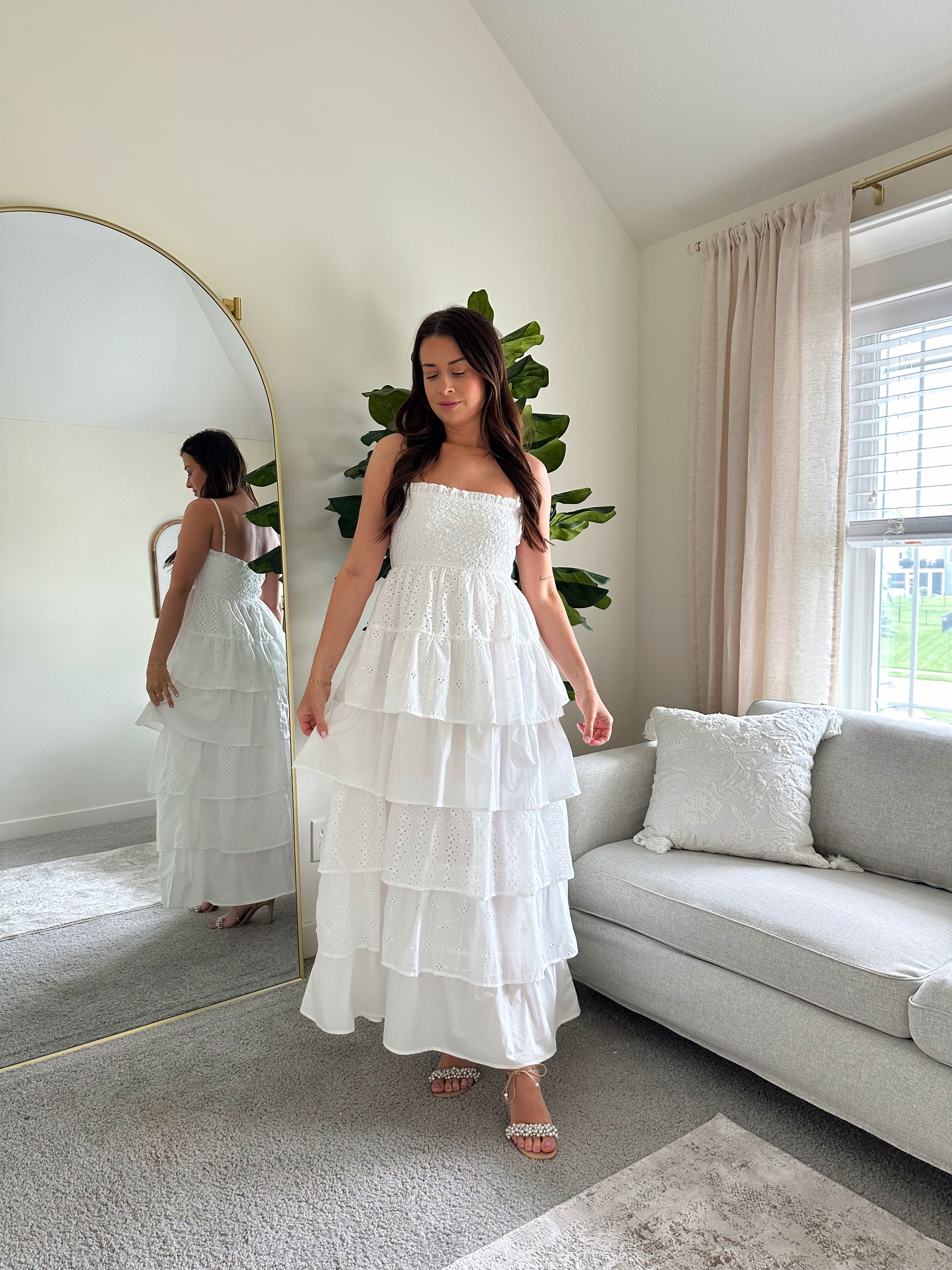 Woman in white smocked midi dress with tiered eyelet fabric and thin straps