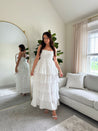 Woman in white smocked midi dress with tiered eyelet fabric and thin straps