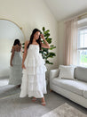 Woman in white smocked midi dress with tiered eyelet fabric and thin straps
