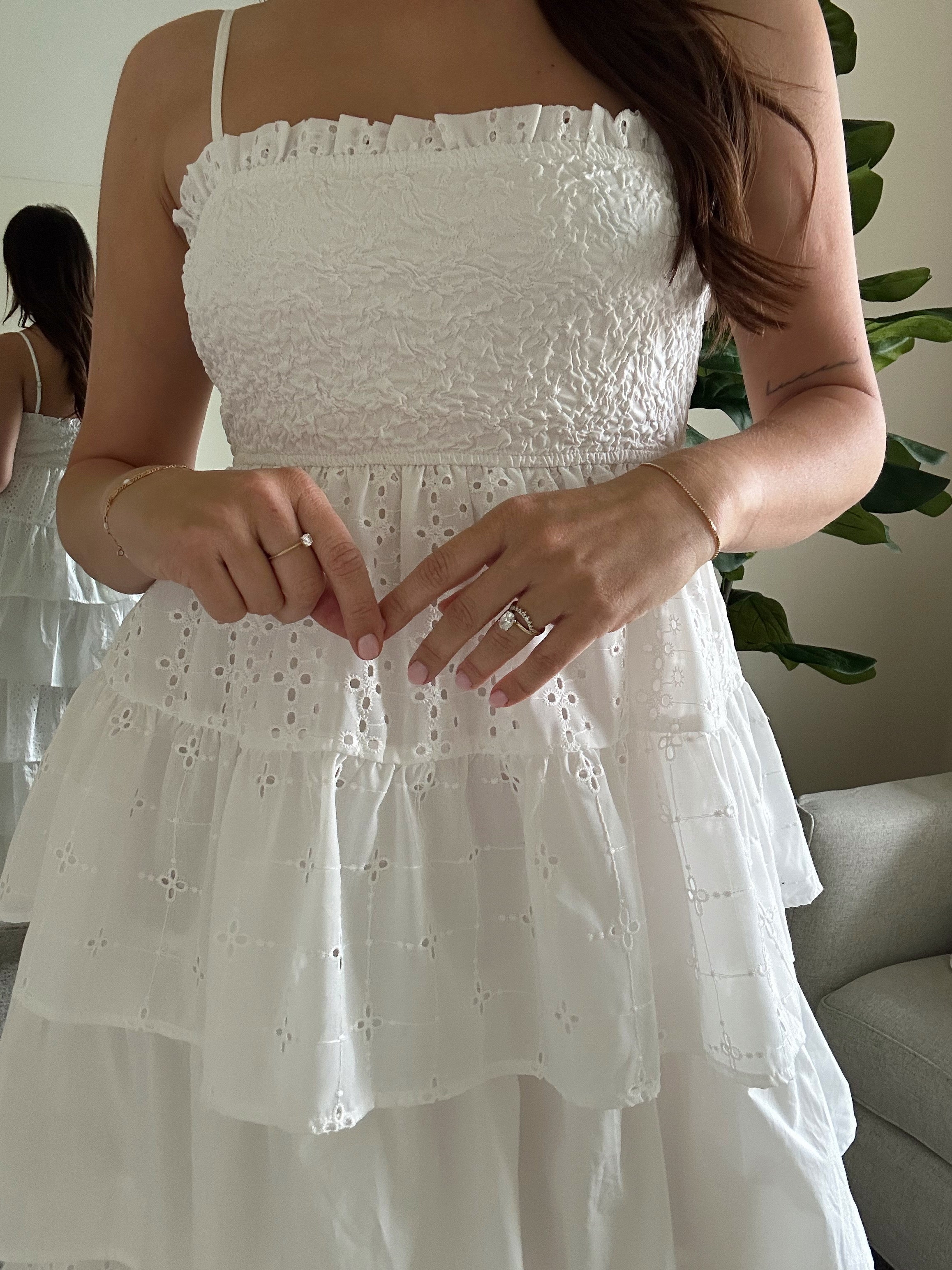 Woman in white smocked midi dress with tiered eyelet fabric and thin straps