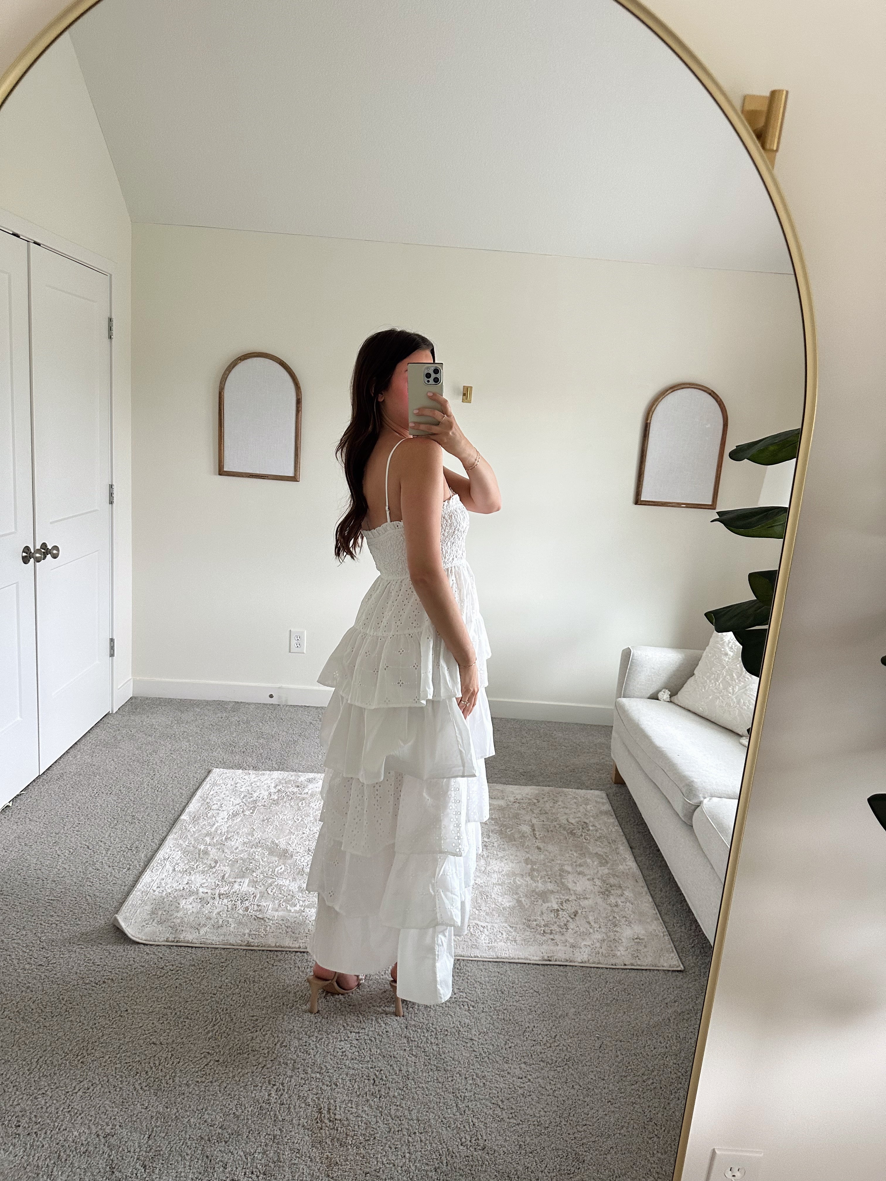Woman in white smocked midi dress with tiered eyelet fabric and thin straps