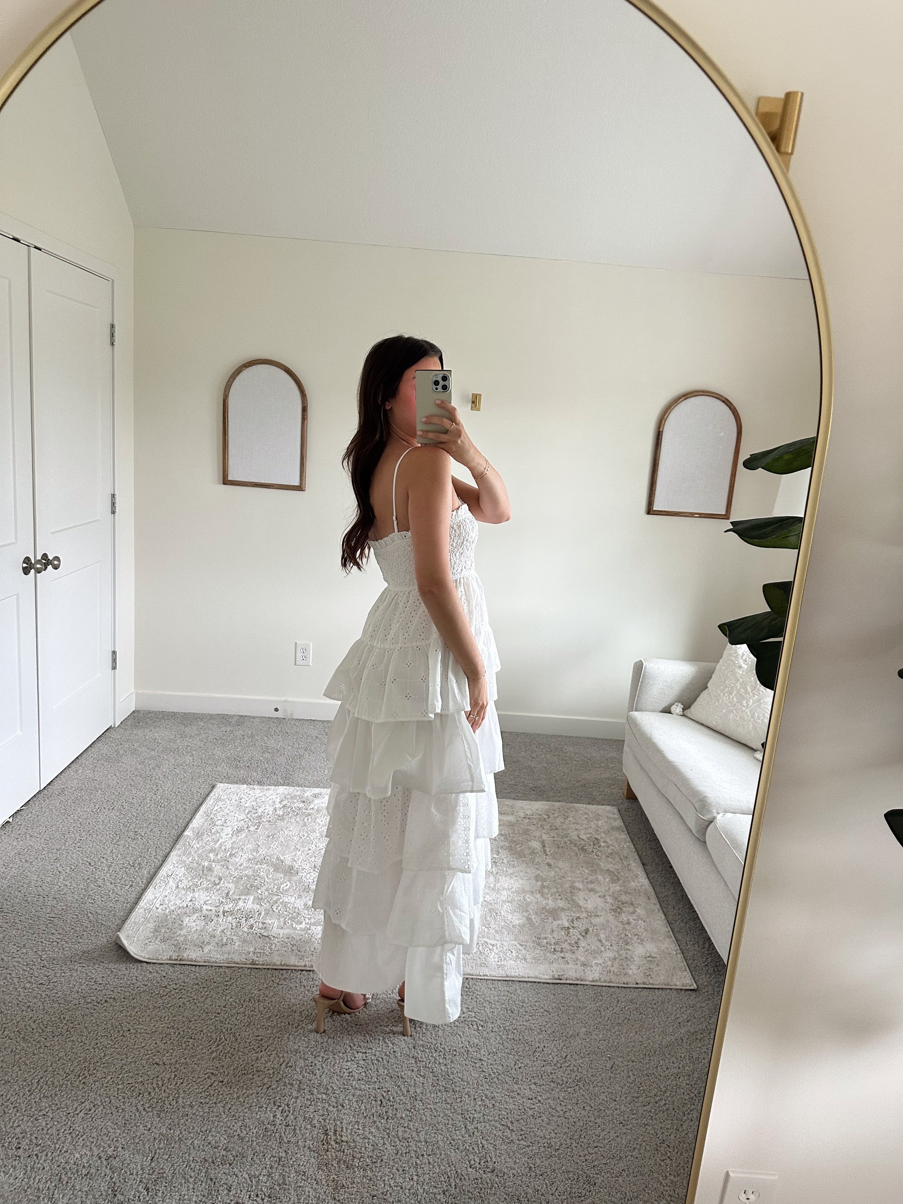 Woman in white smocked midi dress with tiered eyelet fabric and thin straps