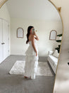 Woman in white smocked midi dress with tiered eyelet fabric and thin straps