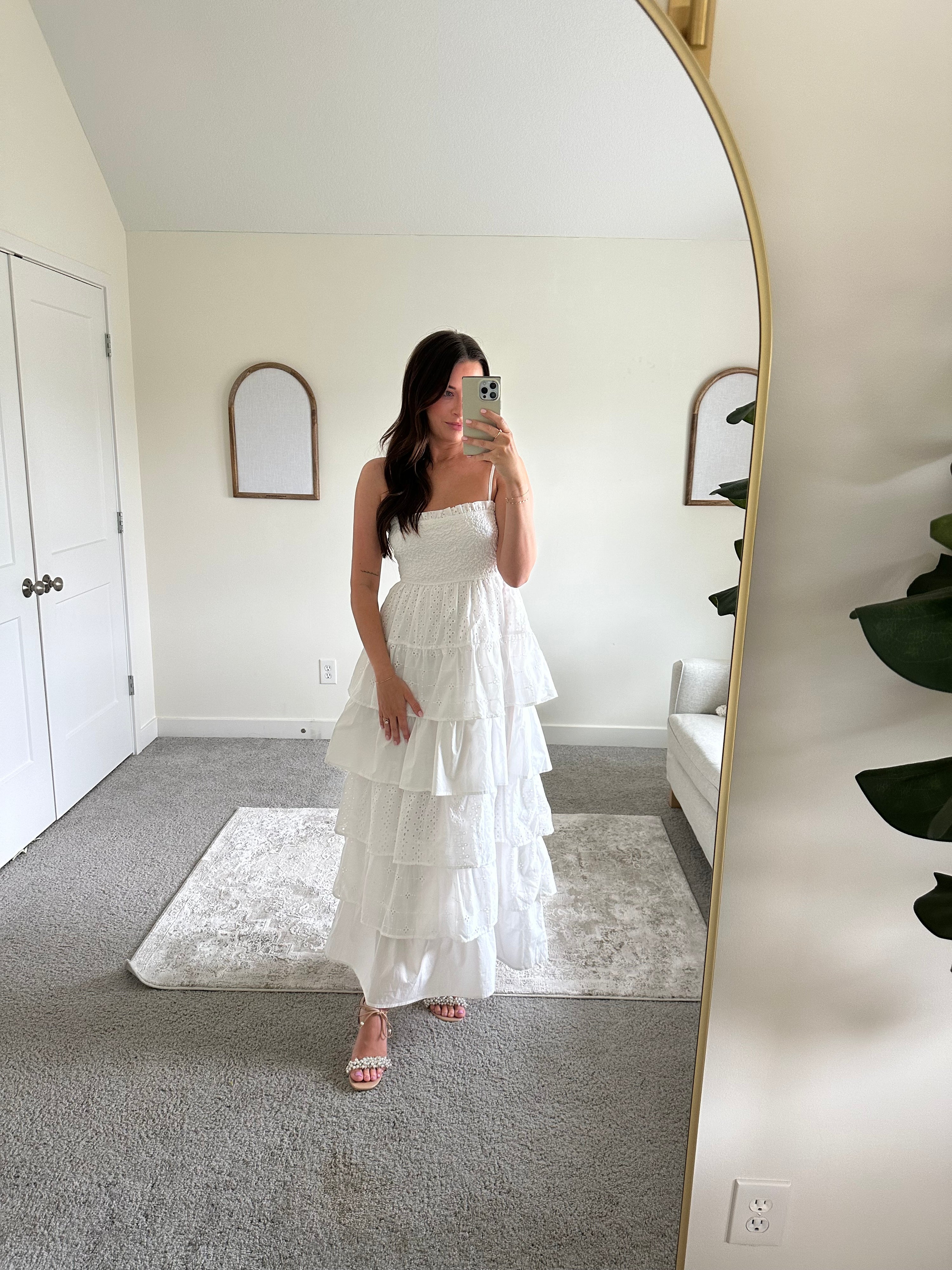 Woman in white smocked midi dress with tiered eyelet fabric and thin straps