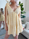 Woman wearing yellow embroidered mini dress with tie straps and floral detail