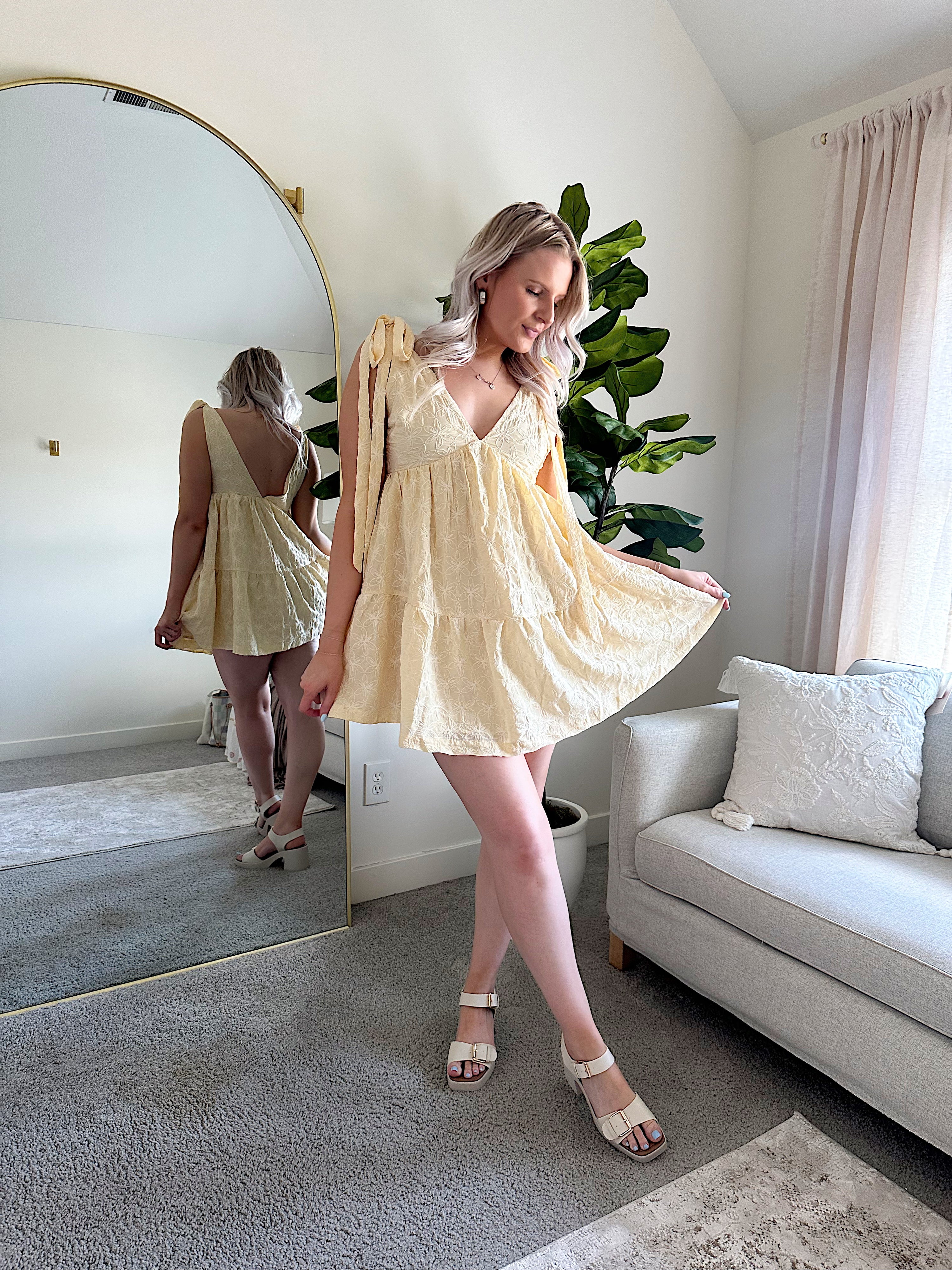 Woman wearing yellow embroidered mini dress with tie straps and floral detail