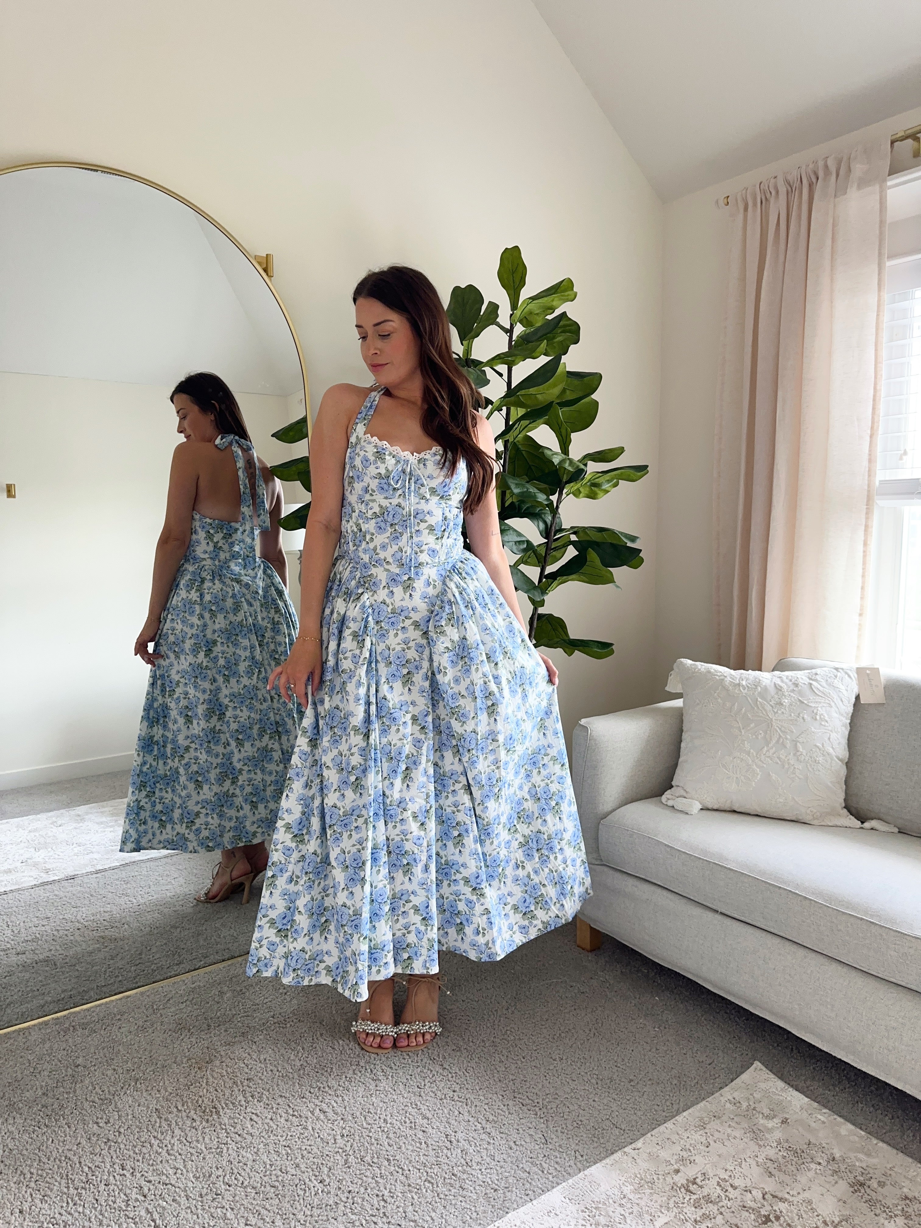Woman in blue floral halter neck midi dress with lace trim and open back