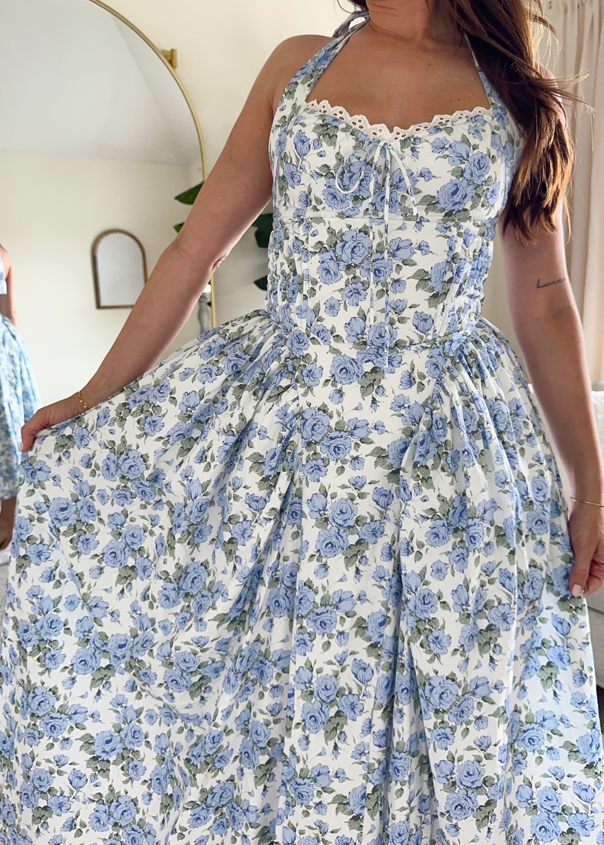 Woman in blue floral halter neck midi dress with lace trim and open back