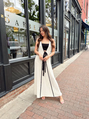Woman in cream knit maxi dress with black piping and detachable black bandeau top