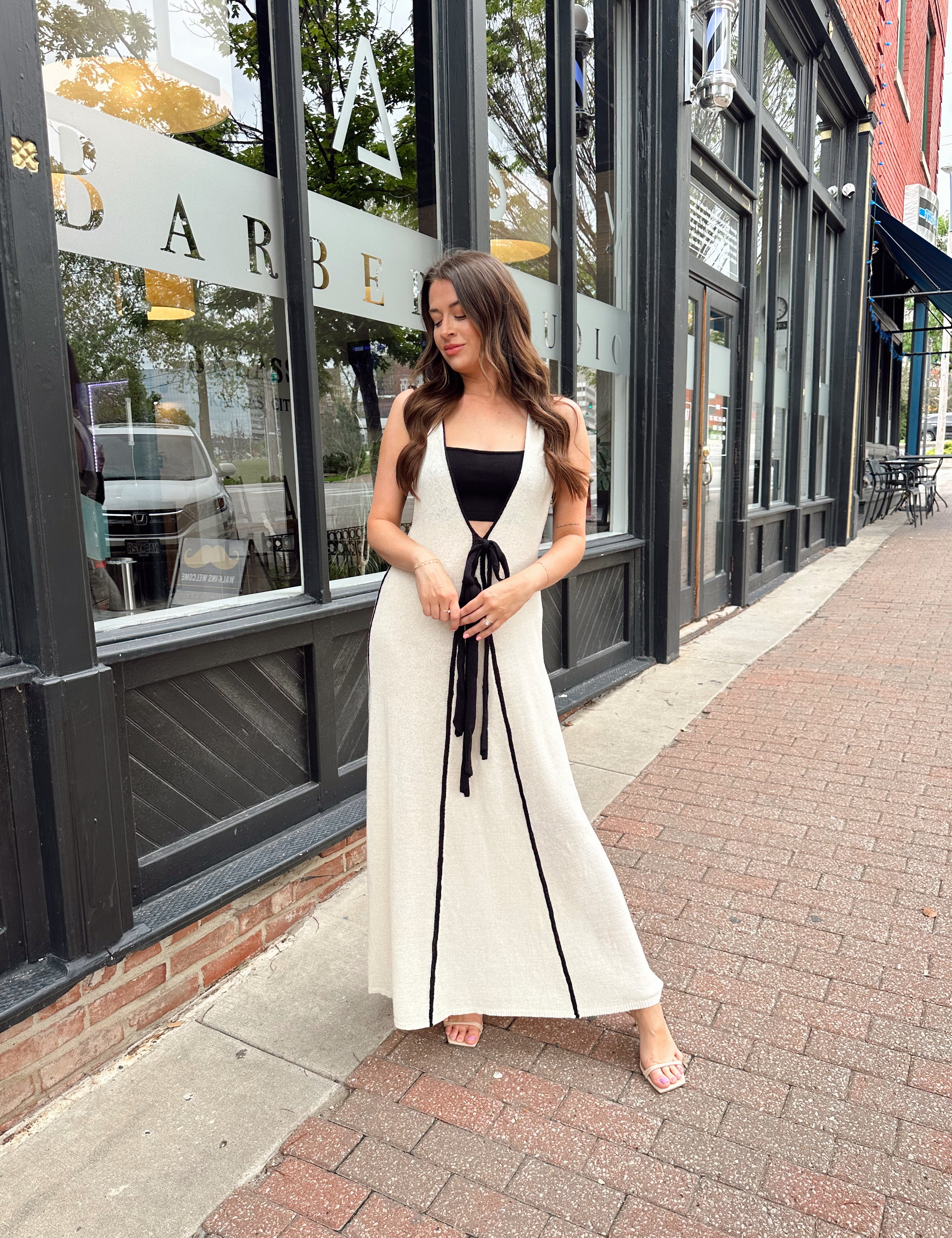 Woman in cream knit maxi dress with black piping and detachable black bandeau top