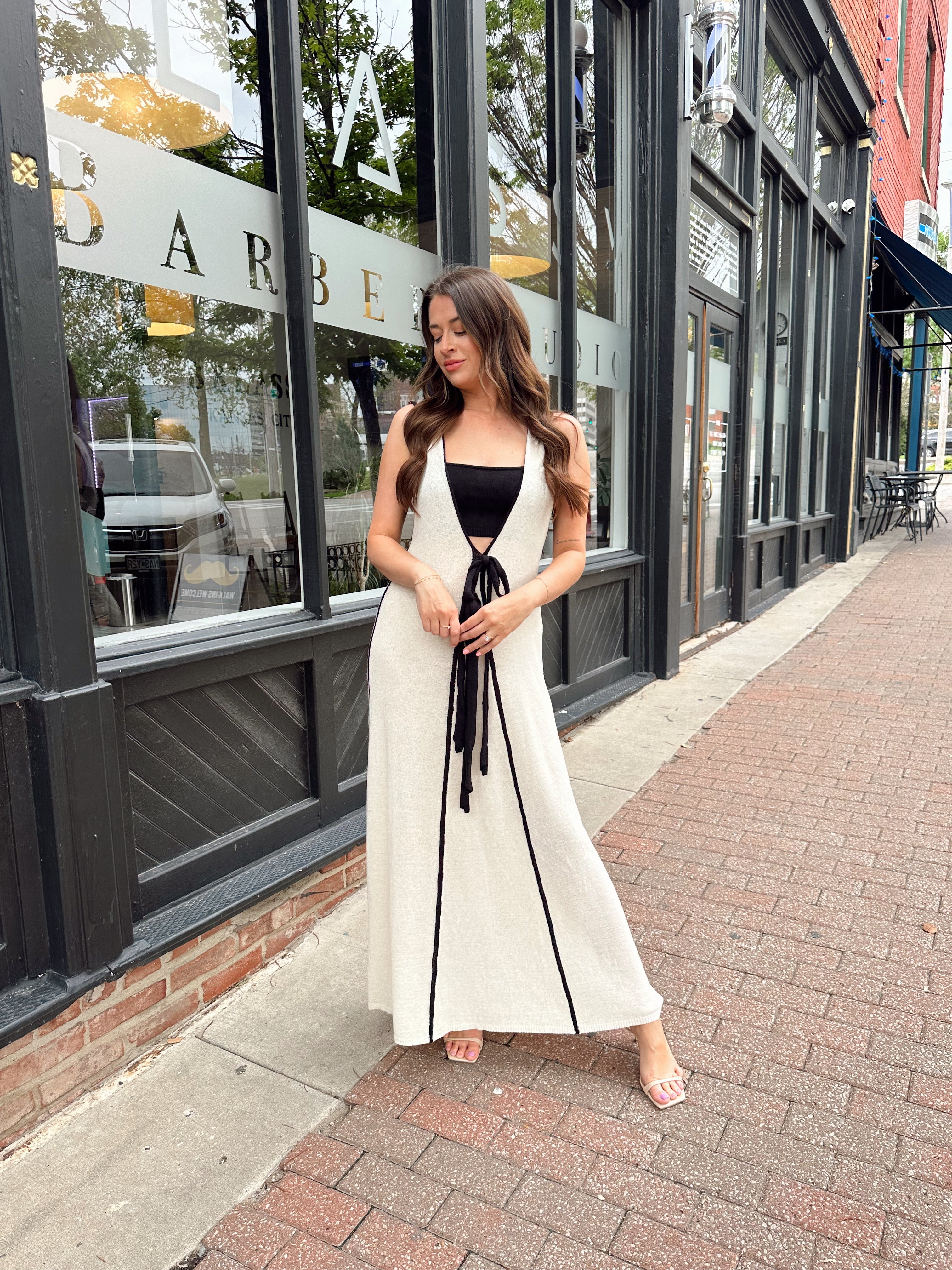 Woman in cream knit maxi dress with black piping and detachable black bandeau top