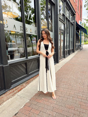 Woman in cream knit maxi dress with black piping and detachable black bandeau top