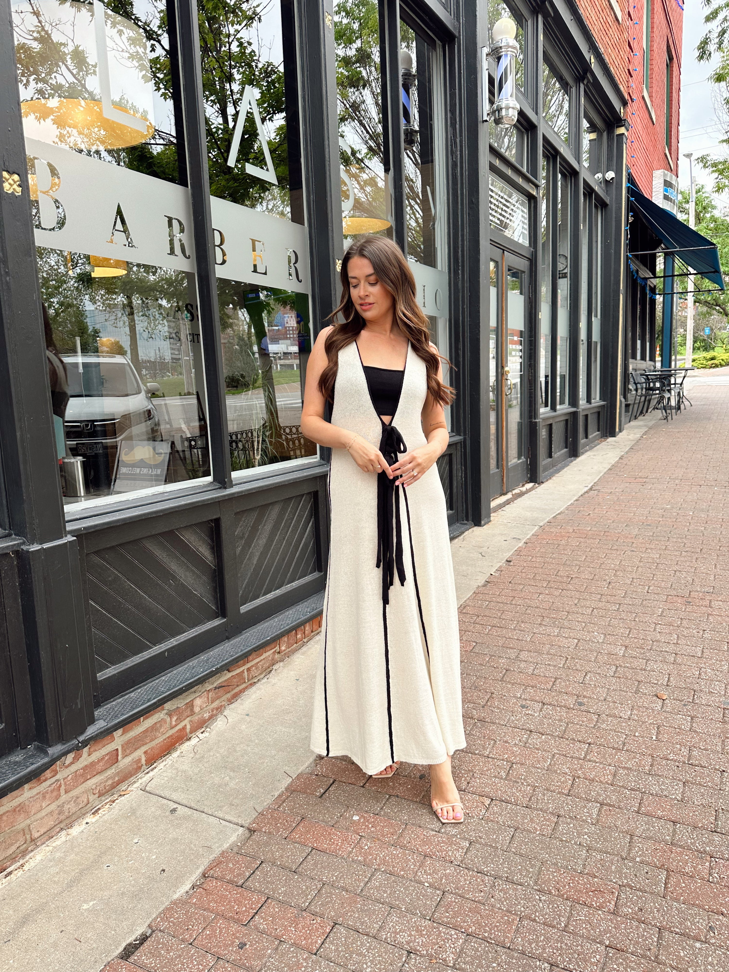 Woman in cream knit maxi dress with black piping and detachable black bandeau top