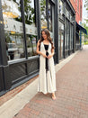 Woman in cream knit maxi dress with black piping and detachable black bandeau top