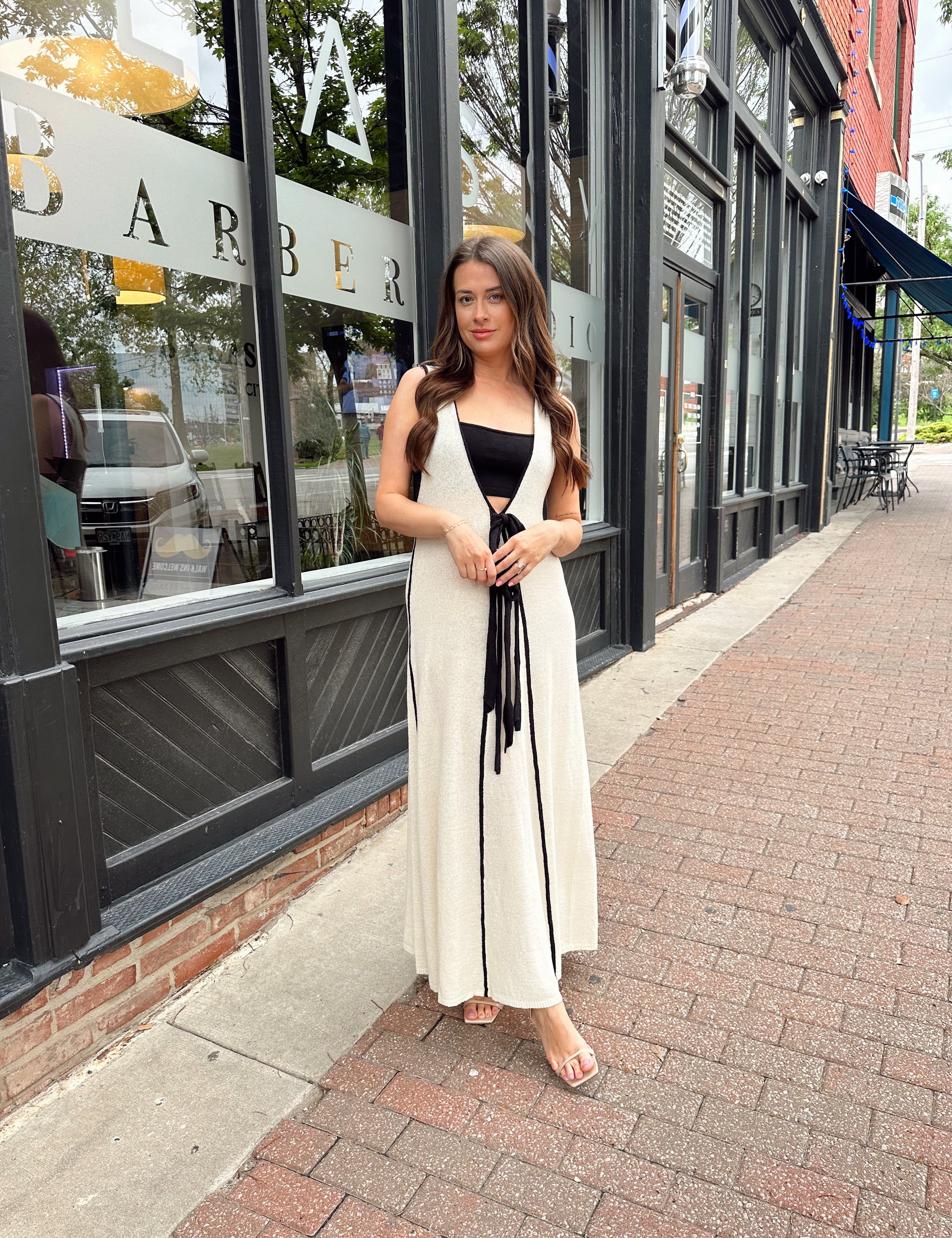 Woman in cream knit maxi dress with black piping and detachable black bandeau top