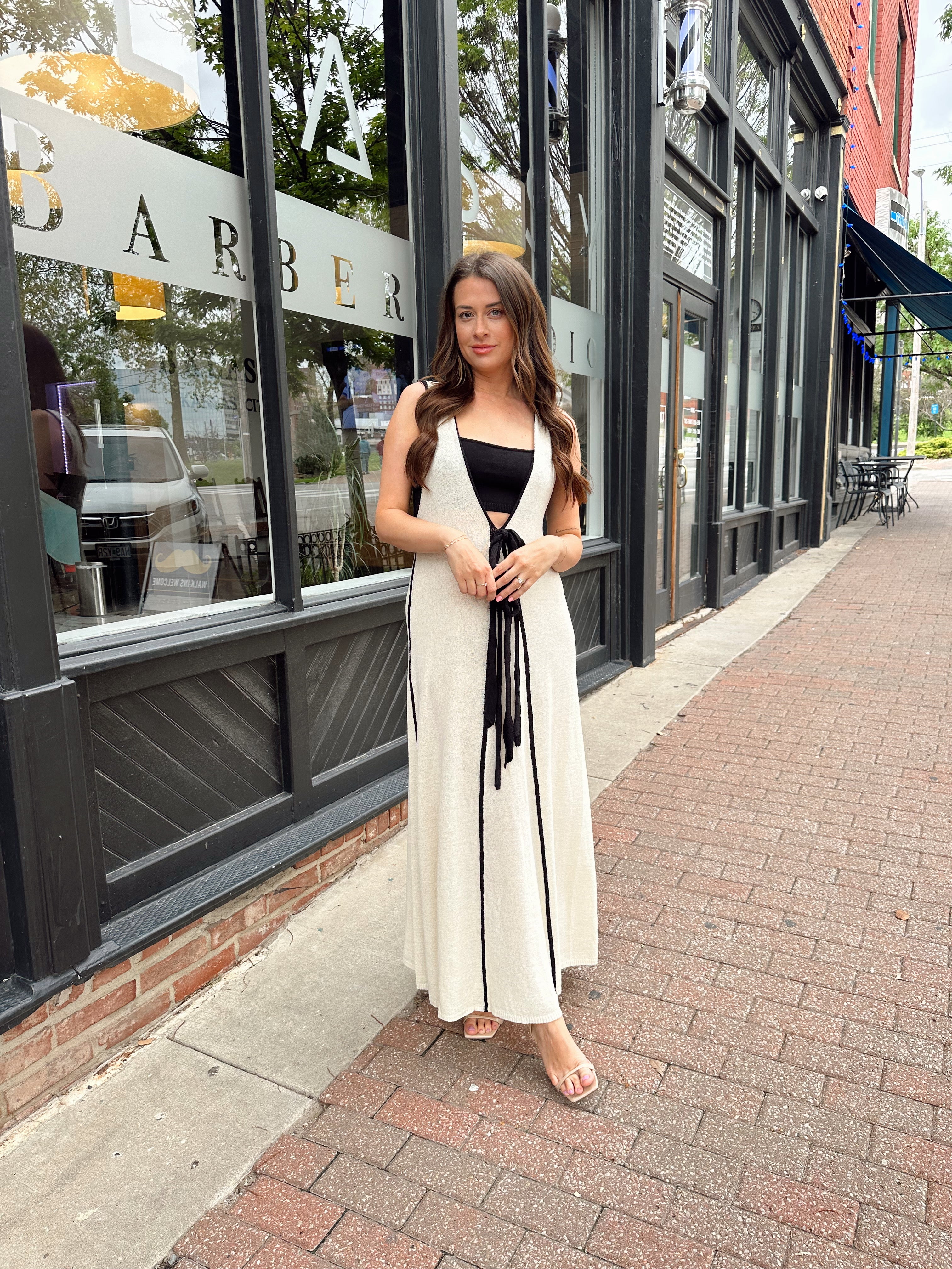 Woman in cream knit maxi dress with black piping and detachable black bandeau top