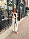 Woman in cream knit maxi dress with black piping and detachable black bandeau top