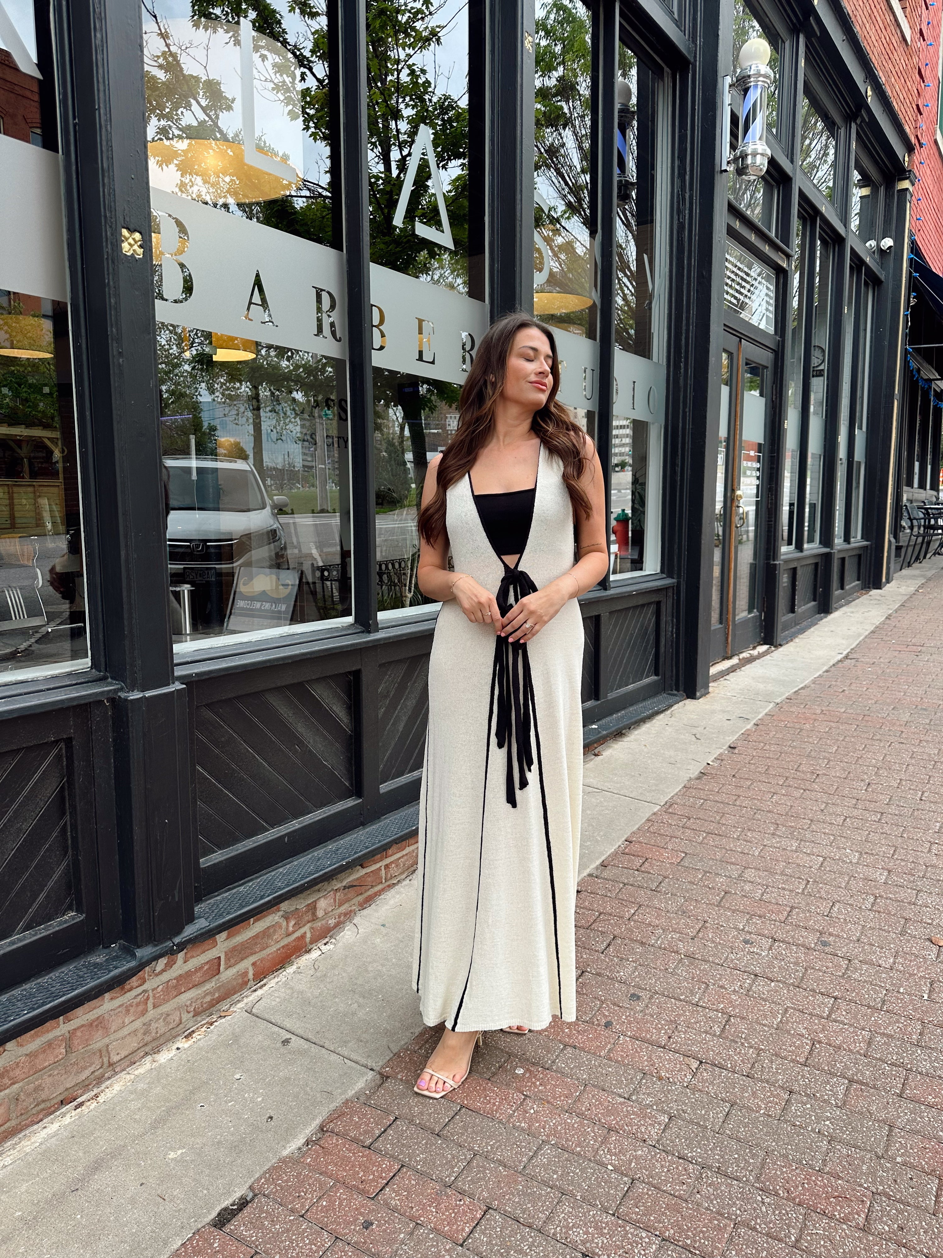 Woman in cream knit maxi dress with black piping and detachable black bandeau top