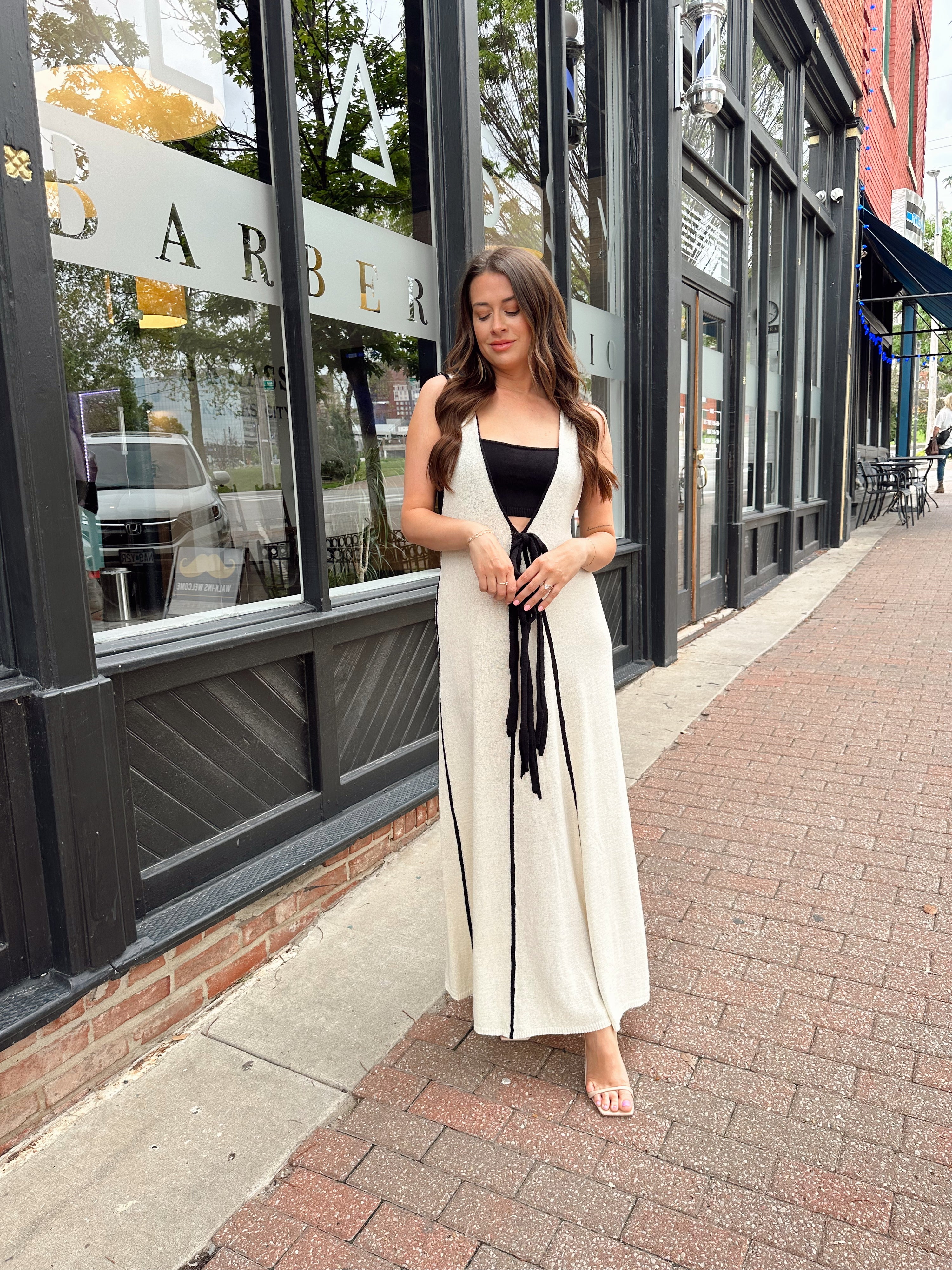 Woman in cream knit maxi dress with black piping and detachable black bandeau top