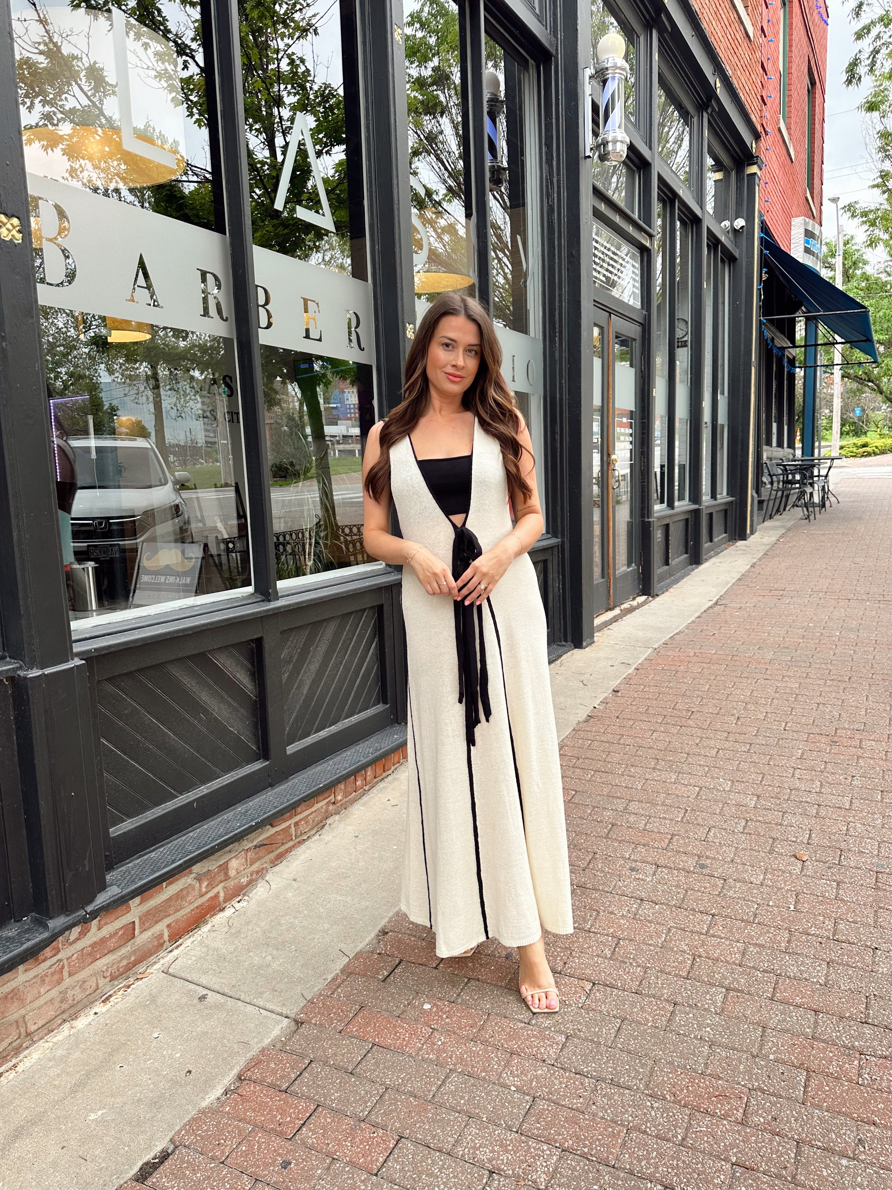 Woman in cream knit maxi dress with black piping and detachable black bandeau top