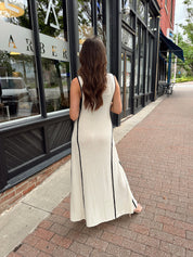 Woman in cream knit maxi dress with black piping and detachable black bandeau top