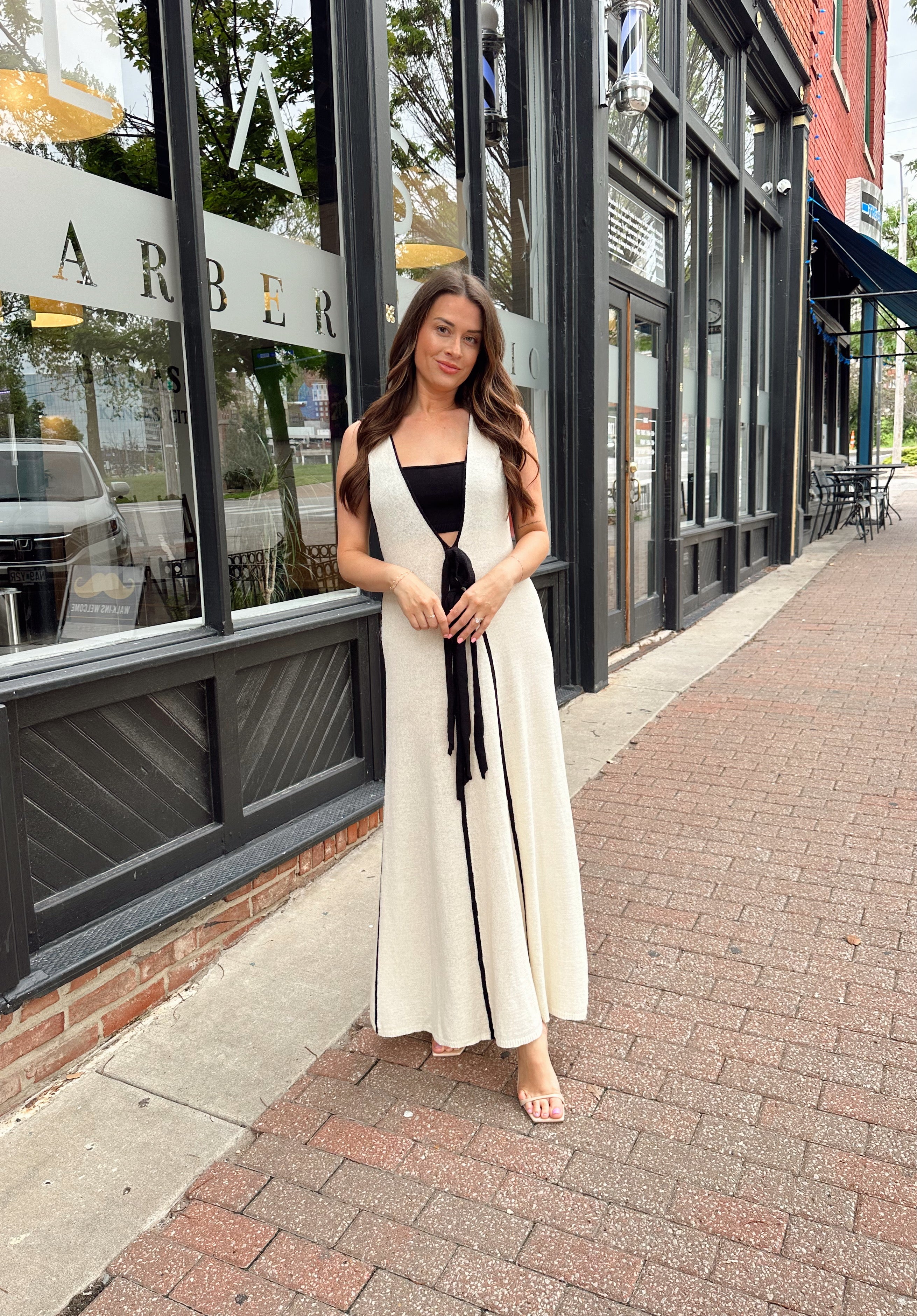 Woman in cream knit maxi dress with black piping and detachable black bandeau top