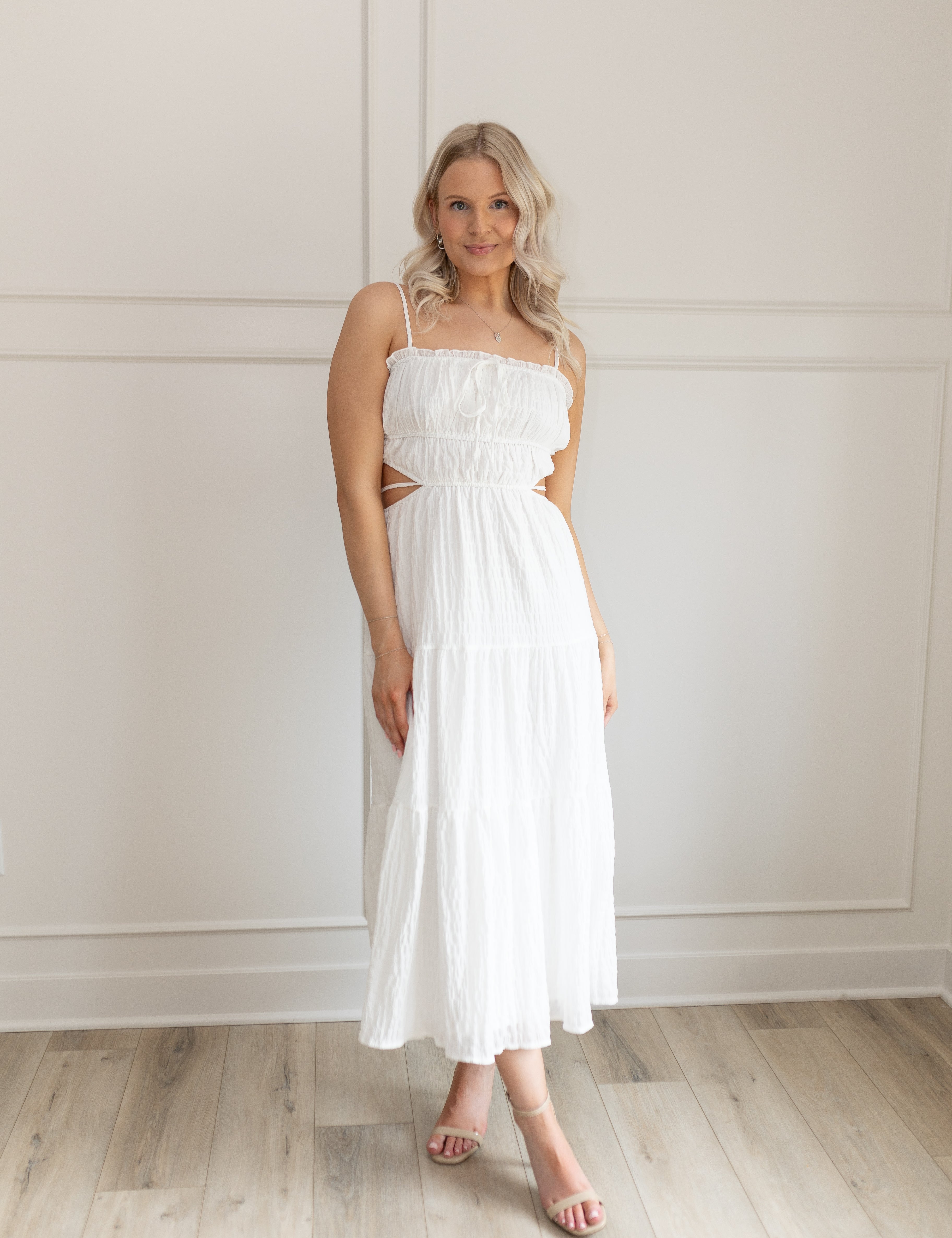 Model wearing white midi dress with side cutouts and smocked bodice