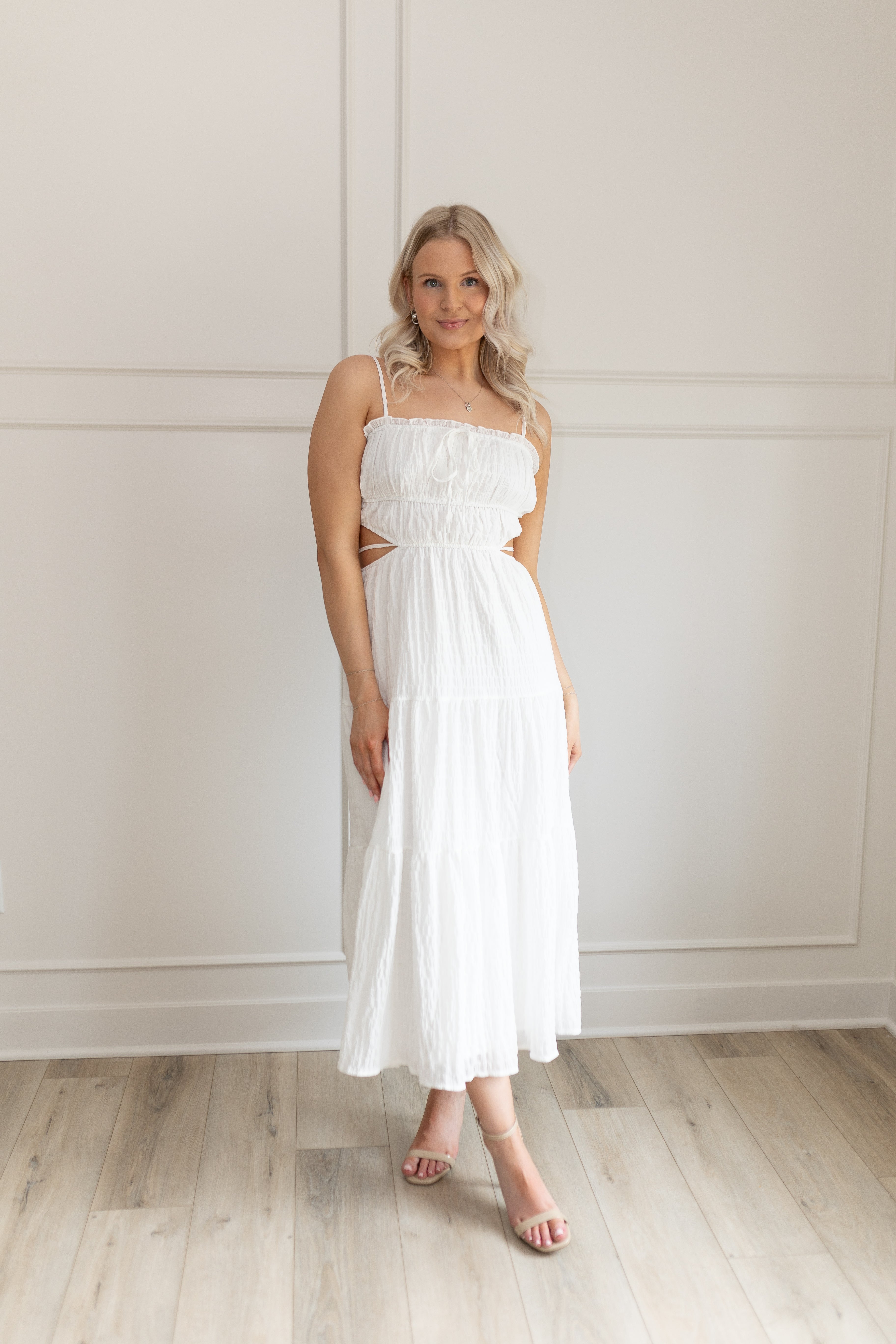 Model wearing white midi dress with side cutouts and smocked bodice