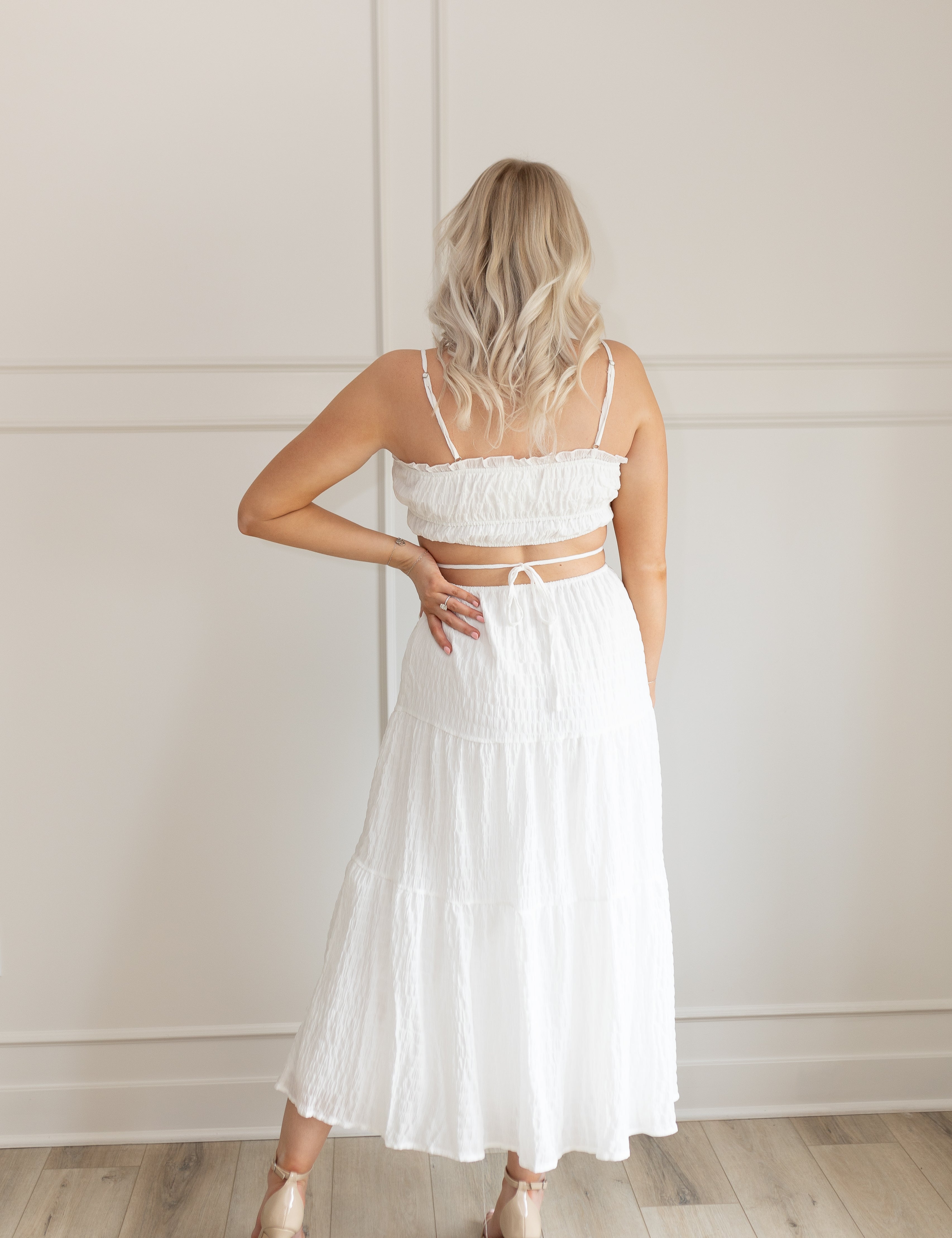 Model wearing white midi dress with side cutouts and smocked bodice