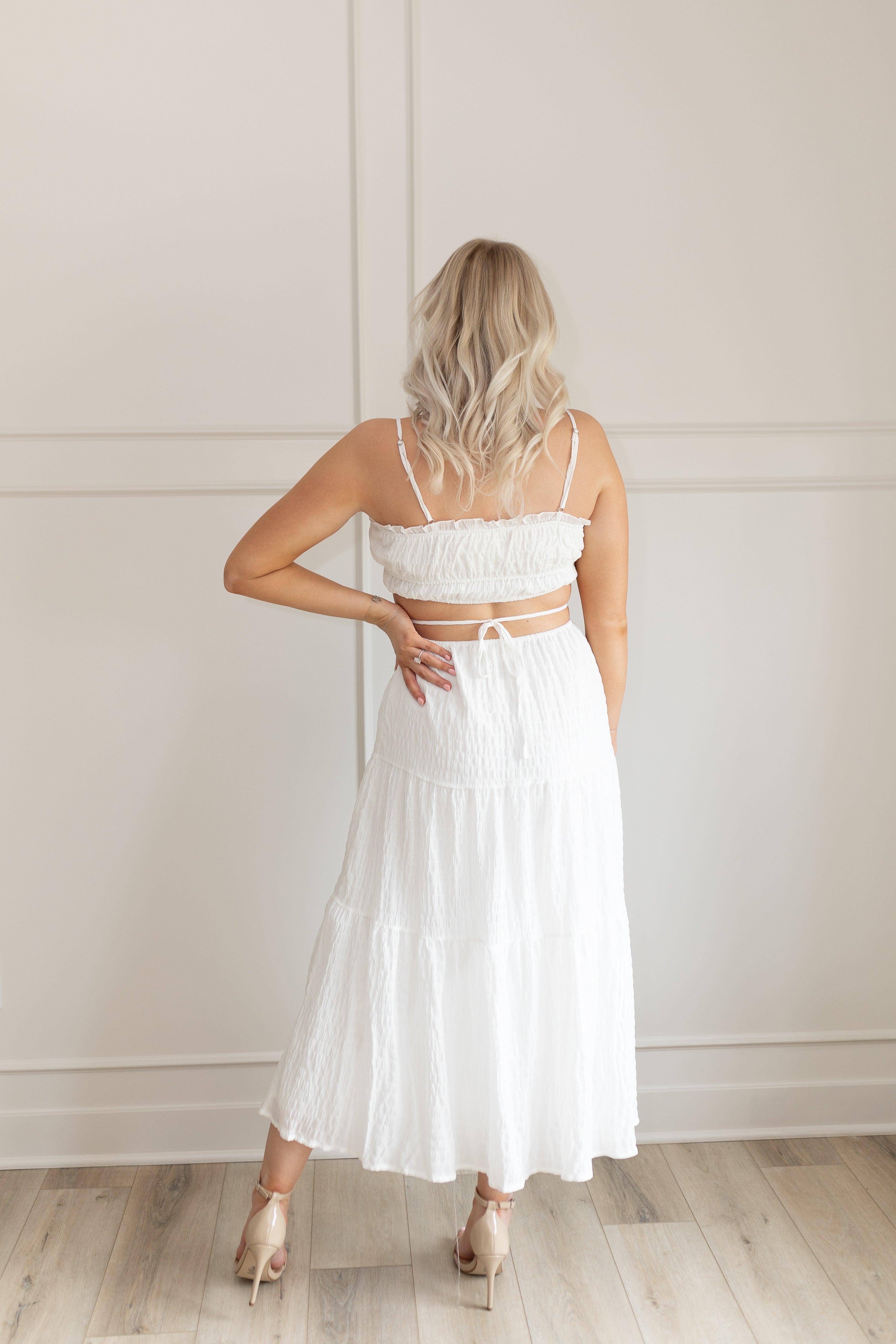 Model wearing white midi dress with side cutouts and smocked bodice