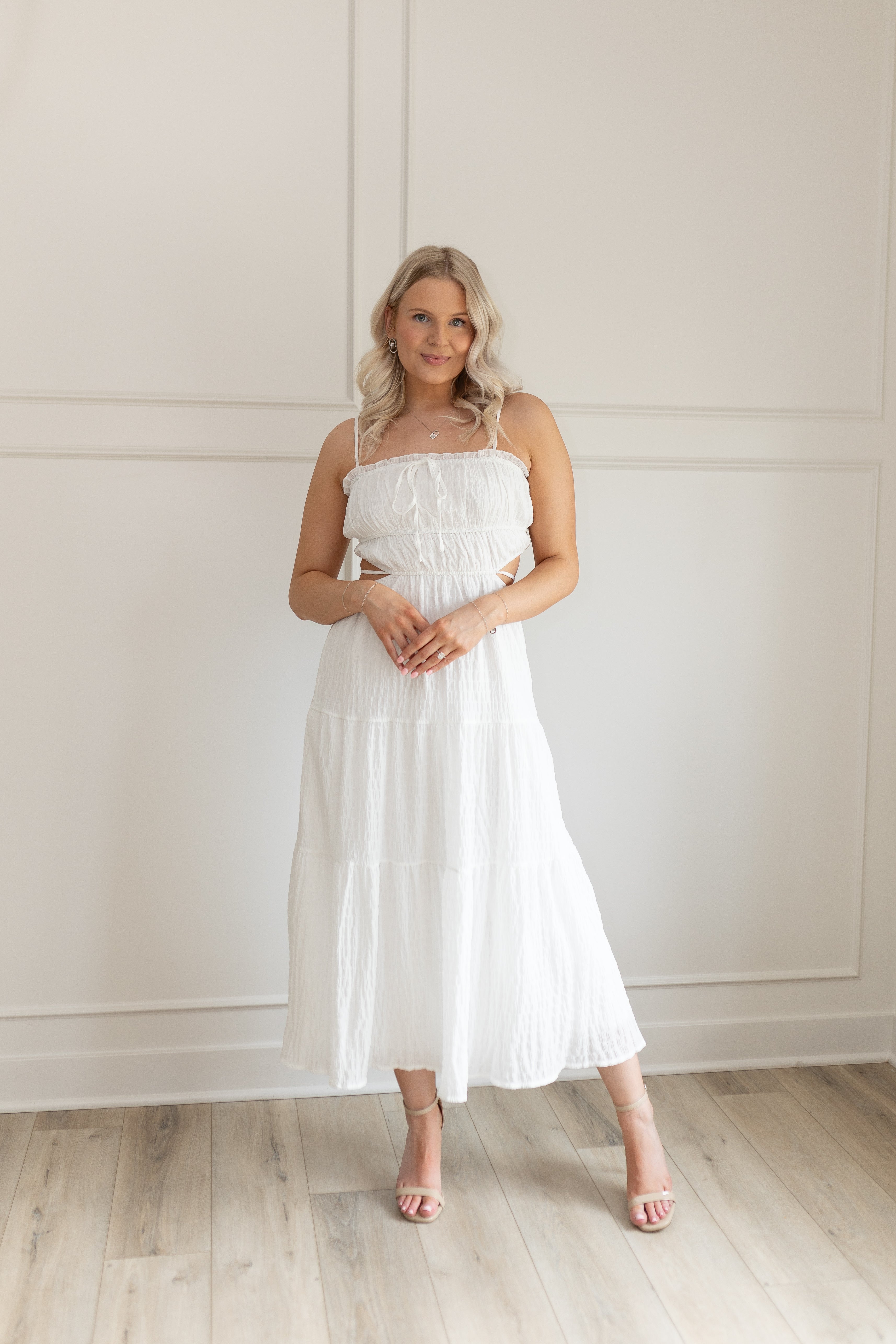 Model wearing white midi dress with side cutouts and smocked bodice