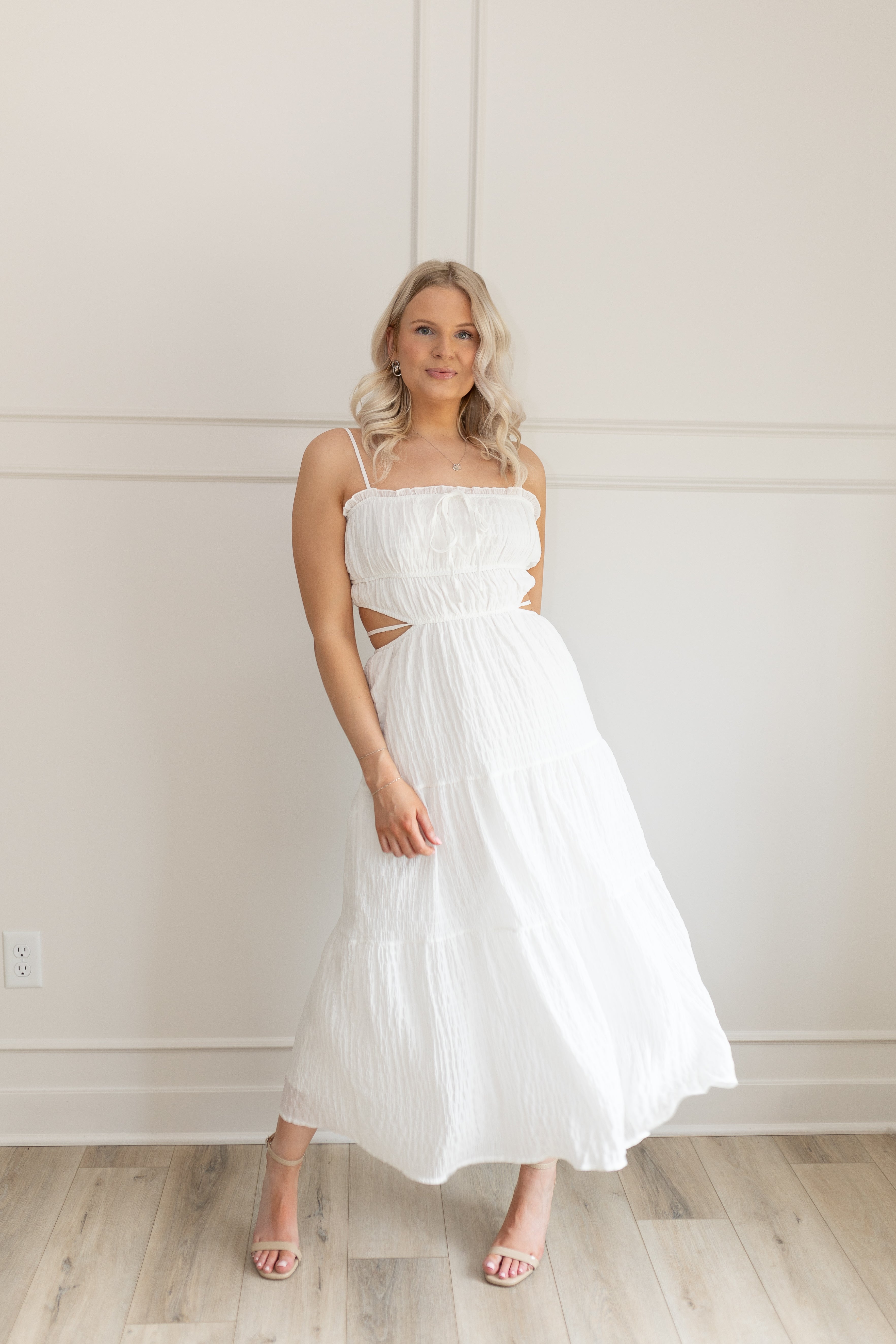 Model wearing white midi dress with side cutouts and smocked bodice
